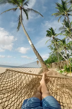 Person relaxing on beach in hammock